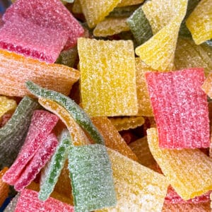 Scherpe, zure fruitrollen in levendige kleuren zoals rood, geel, groen en oranje, met een lichtzure bite en een zoete afdronk. Deze kleurrijke snoepjes bieden een heerlijke balans van smaken.