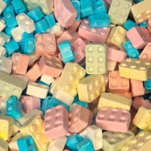 Speelse blokvormige snoepjes in zachte pastelkleuren, waaronder blauw, roze, geel en wit. Deze kleurrijke snoepjes roepen herinneringen op aan bouwstenen en bieden een knapperige en zoete ervaring bij elke hap.